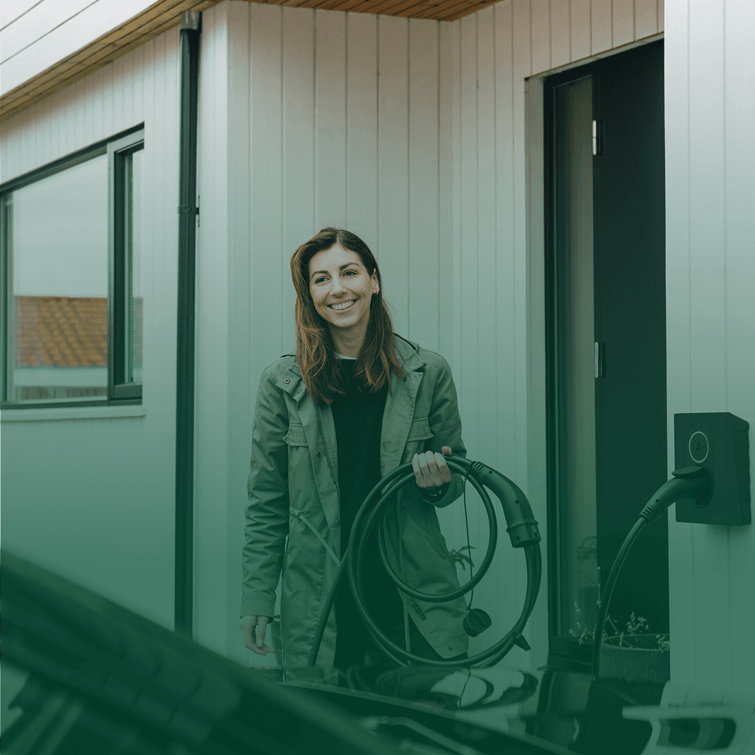 Kvinde står med ladekabel i hånden